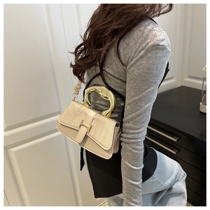 Detail shot of cream shoulder bag featuring woven texture flap and golden U-shaped handle