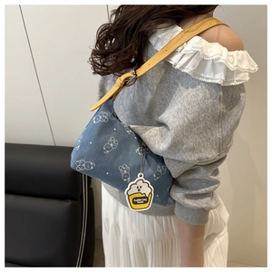 Detail of blue denim shoulder bag with white bear print and yellow leather strap