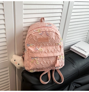 Detailed close-up of pink quilted backpack with ribbon bows and cloud charm pendant