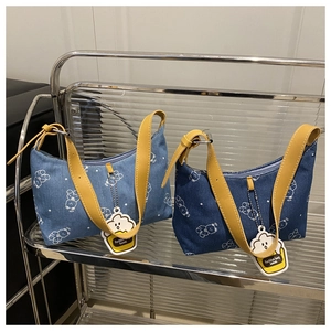 Close-up of denim shoulder bags with white bear prints and yellow leather straps