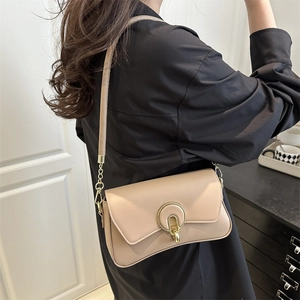Minimalist apricot leather crossbody bag with a distinctive golden horseshoe buckle closure