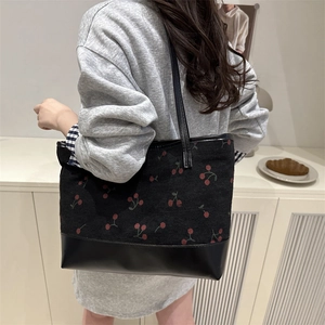 Stylish black tote bag with red cherry print and leather handles for casual daily use