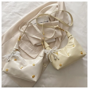 Détail du mini sac seau en cuir verni brillant avec clous ours et nœud en dentelle
