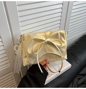 Detailed view of the champagne gold bow and pearl lace charms on the stylish shoulder bag