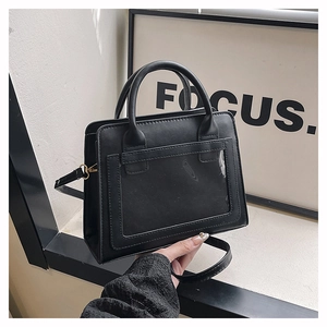 Detail of black PU leather handbag with unique transparent PVC front pocket and gold hardware