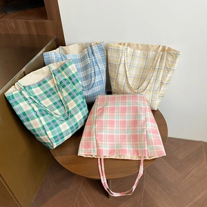 Detailed view of four colorful checkered canvas tote bags in a casual lifestyle setting