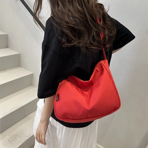 Minimalistische rote Umhängetasche aus Nylon für Damen getragen im urbanen Stil