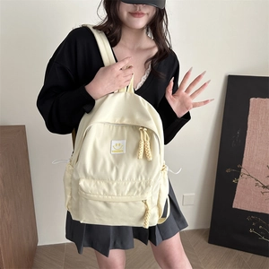 Minimalist cream nylon backpack for students featuring a yellow smiley face patch and drawstrings
