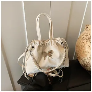 Close-up of cream butterfly drawstring bag with pearl handle and metal hardware