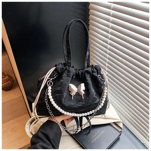 Detail of black pleated cloud bag with silver butterfly charm and pearl chain decoration