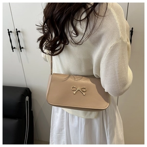 Détail du sac à bandoulière abricot avec un fermoir décoratif en forme de nœud doré