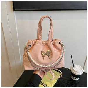 Close-up of pink pleated fabric bag with golden butterfly and elegant pearl chain