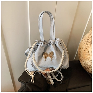 Close-up of light blue drawstring bag featuring golden butterfly and pearl chain strap