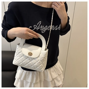 Detail of white quilted bag showing gold twist lock and leather woven chain strap