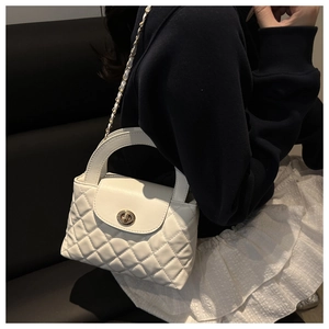 Detailed view of white quilted crossbody bag with gold metal twist lock and chain strap