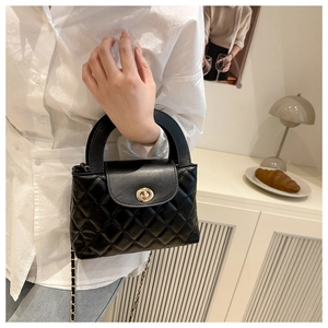 Close-up of black quilted leather handbag with gold metal clasp and chain strap