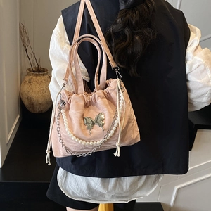 Pink drawstring bucket backpack with silver butterfly charm and pearl chain accent