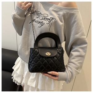 Black quilted crossbody bag with gold twist lock and chain strap on a model