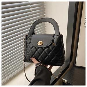 Close-up of black quilted handbag featuring a golden twist lock and luxury chain strap