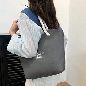 Gray canvas tote bag with woven rope handles and white fashion lettering print