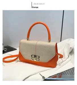Detail of orange leather shoulder bag featuring woven flap and golden interlocking buckle