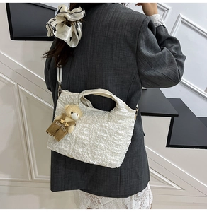 Détail du sac seau blanc à texture froissée avec charmant pendentif ours mode