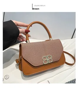 Detailed close-up of brown leather handbag with golden logo buckle and herringbone flap