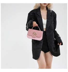 Detail of pink patchwork crossbody bag with textured weaving and round metal M buckle