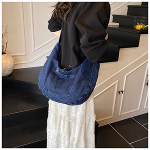Detail shot of blue denim hobo bag featuring decorative front pocket and vintage stitching