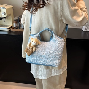 Sac seau plissé bleu clair avec breloque ours présenté dans un cadre de vie chaleureux