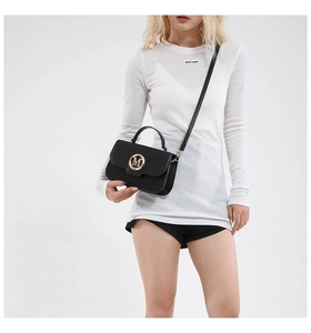 Side view of a black leather handbag with a gold M logo on a model in a white studio