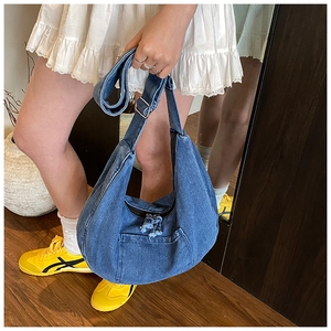 Détail de la bandoulière réglable et boucle argentée sur grand sac hobo en jean bleu