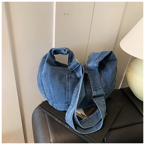Détail du sac bandoulière en jean bleu foncé avec boucle métallique et sangle ajustable