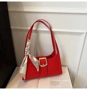 Détail du sac baguette rouge motif crocodile avec boucle dorée et accessoire foulard