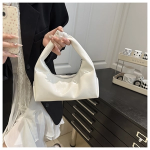 Close-up of a white patent leather croissant bag featuring a glossy mirror finish and zipper