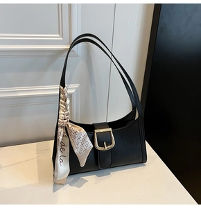 Détail du sac baguette noir texture crocodile avec boucle dorée et foulard en soie à motif