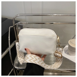 Detailed shot of white leather crossbody bag with wide ethnic geometric embroidery strap