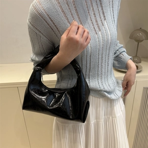 Minimalist black glossy crescent hobo bag with sleek patent leather texture and a stylish handle