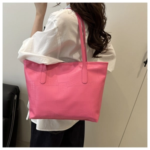 Pink faux leather tote bag with crocodile texture worn by a model for daily commute
