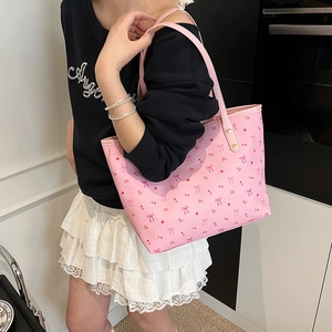 Pink tote bag with cherry and bow prints worn by a model in a casual indoor setting