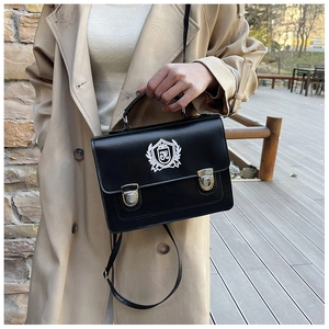 Detailed view of black PU leather school bag with silver buckles and shield embroidery
