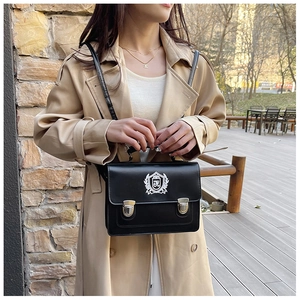 Detail of JK uniform bag featuring shield embroidery and metallic buckles on black leather