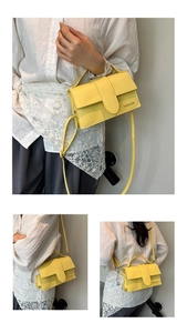 Detail view of a vibrant yellow leather shoulder bag with FASHION lettering worn by a model