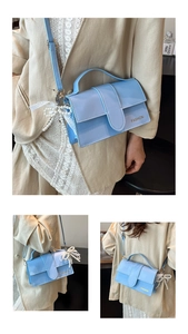Detail of light blue glossy handbag featuring a white lace bow and pearl pendant charm