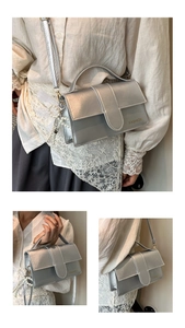 Detailed view of silver metallic shoulder bag with golden fashion text and pearl lace charm