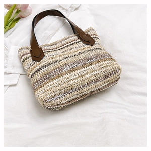 Detail of striped straw bag featuring leather handle attachments and woven texture