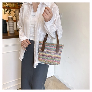 Detail of colorful rainbow striped woven straw bag with premium brown leather handles