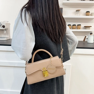 Chic beige vintage crossbody bag with golden lock and fashion pendant in urban cafe setting