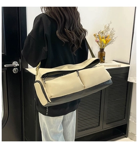 Adjustable shoulder strap detail on a beige and black multifunctional travel duffel bag