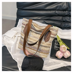 Detailed macro view of the striped woven straw texture and leather handles of the tote bag